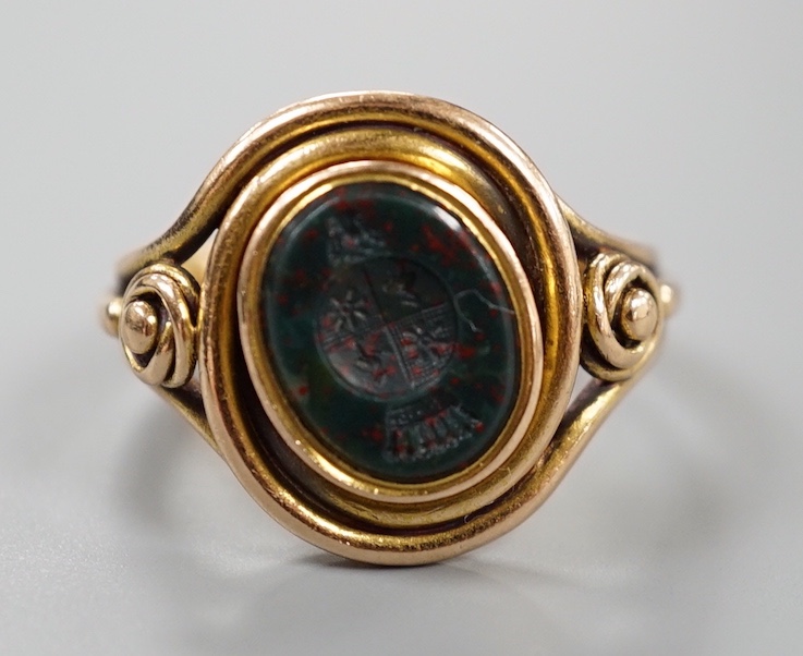 A Victorian yellow metal and oval bloodstone set signet ring, the matrix carved with family crest, size O, gross weight 8.6 grams.